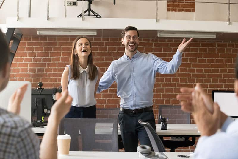 smiling business male and female stand in front of crowd