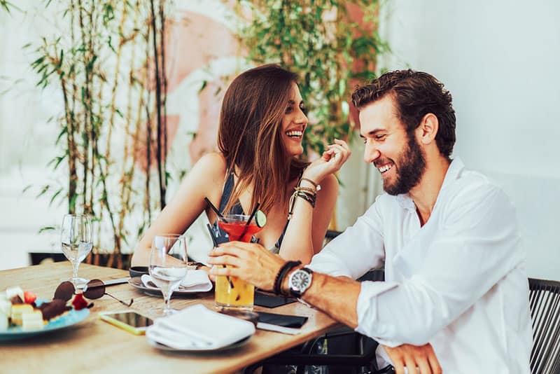 pareja sonriente hablando en un bar de cocteles