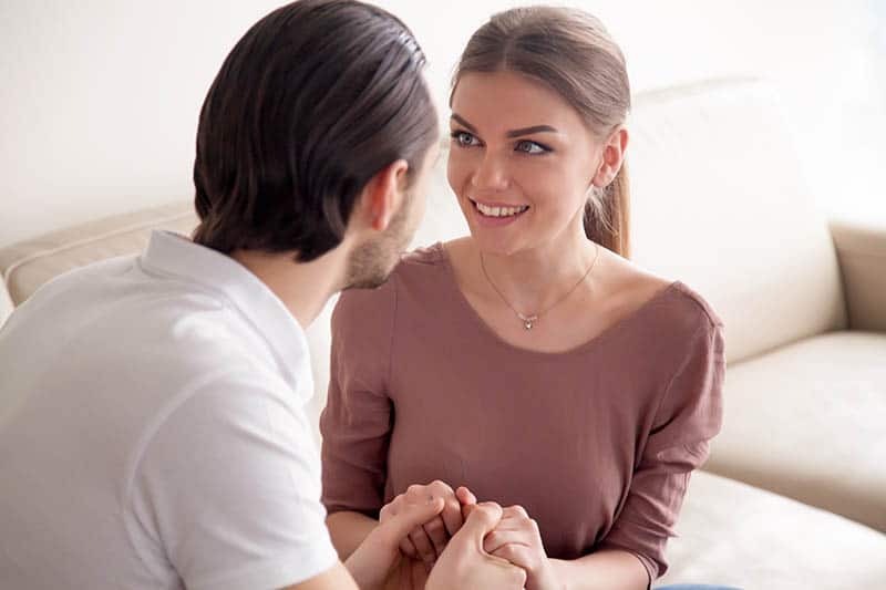 uomo e donna sorridenti che si tengono per mano in casa