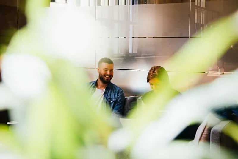 smiling man looking at woman laptop at cafe