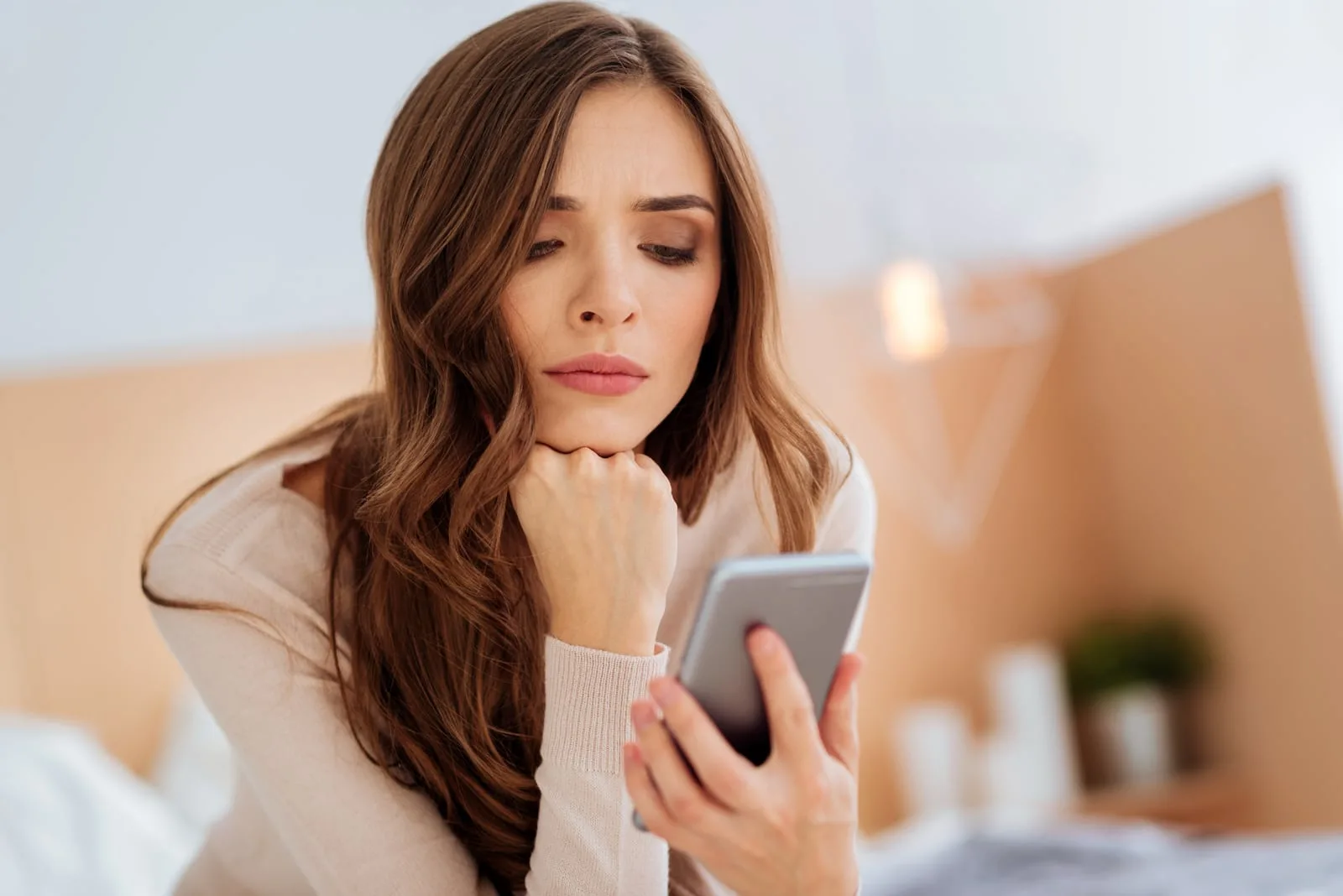 the woman sits pensively and holds the phone in her hand