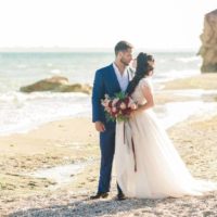 el novio y la novia se miran junto al mar