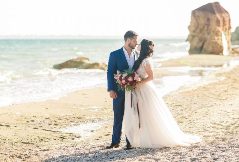 groom and bride looking each other beside sea