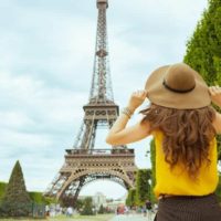 woman wearing hat standing in front of eiffel tower