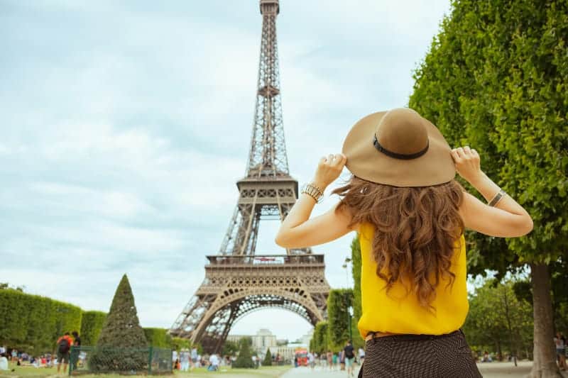 woman wearing hat standing in front of eiffel tower