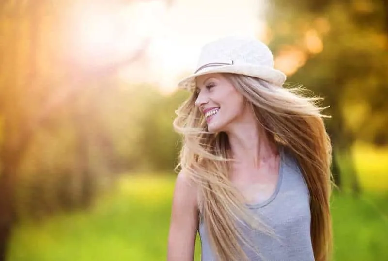 Attractive young woman enjoying her time outside in park with sunset in background.