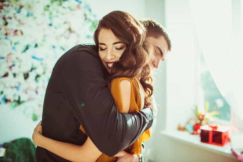 Beautiful lady leans to man's shoulder while he hugs her