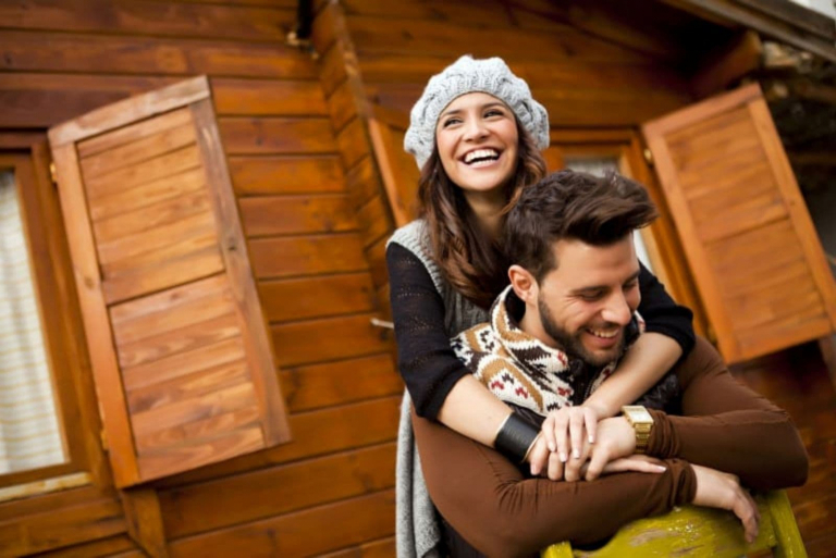 a smiling loving couple hugging in front of the cottage