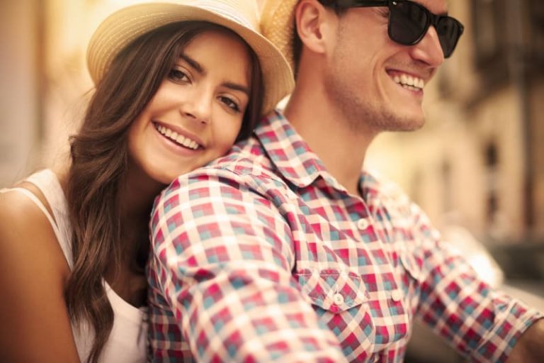 mujer sonriente con sombrero y apoyada en un hombre