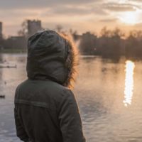 una persona con una capucha en la cabeza observa la puesta de sol