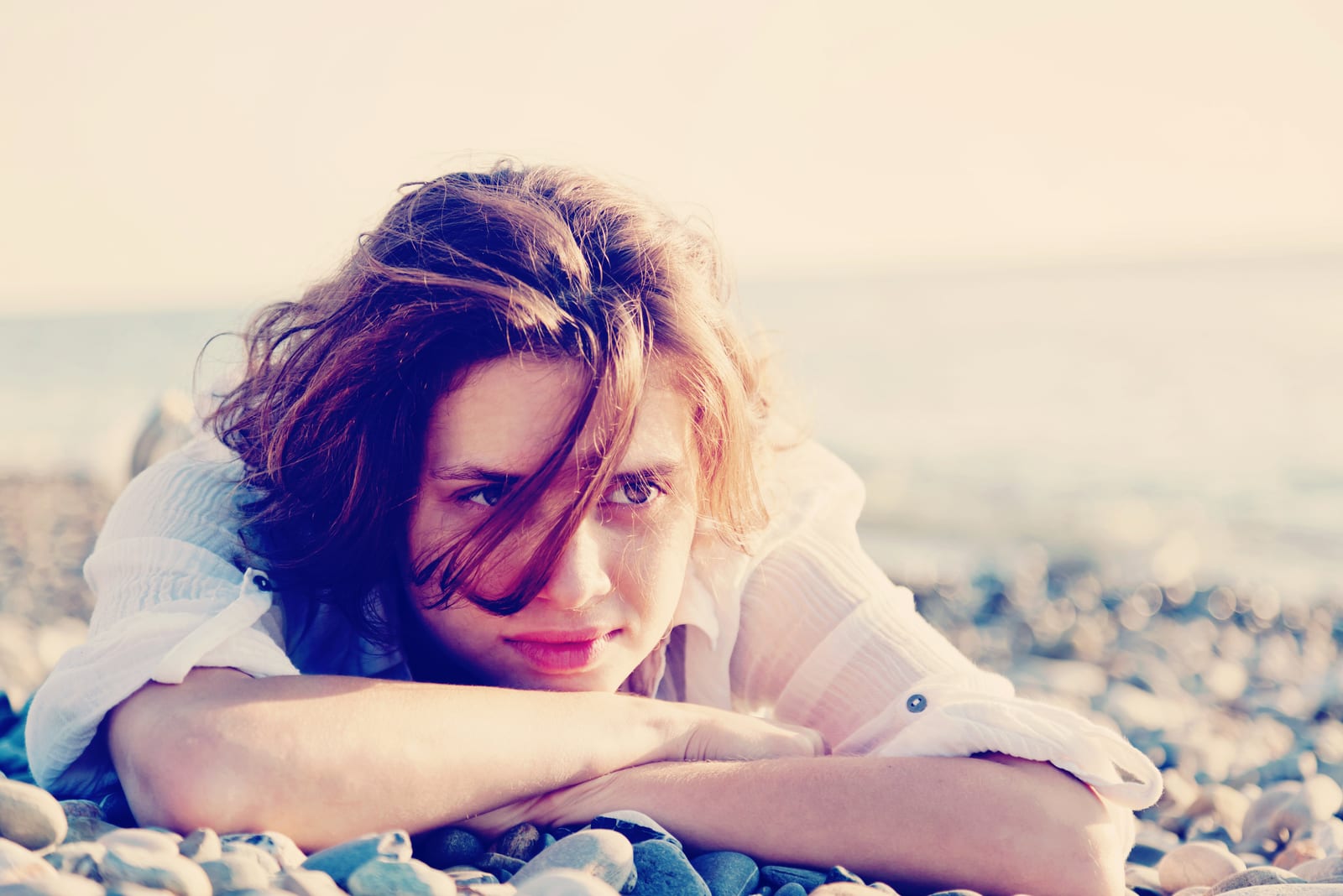 a beautiful woman lying on the beach and thinking