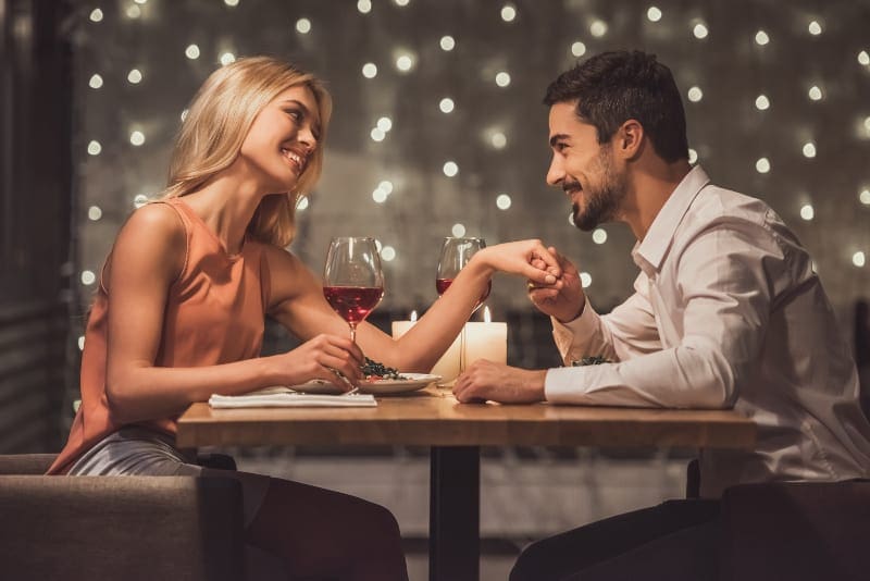 una coppia felice che beve vino da una cassa e si tiene per mano