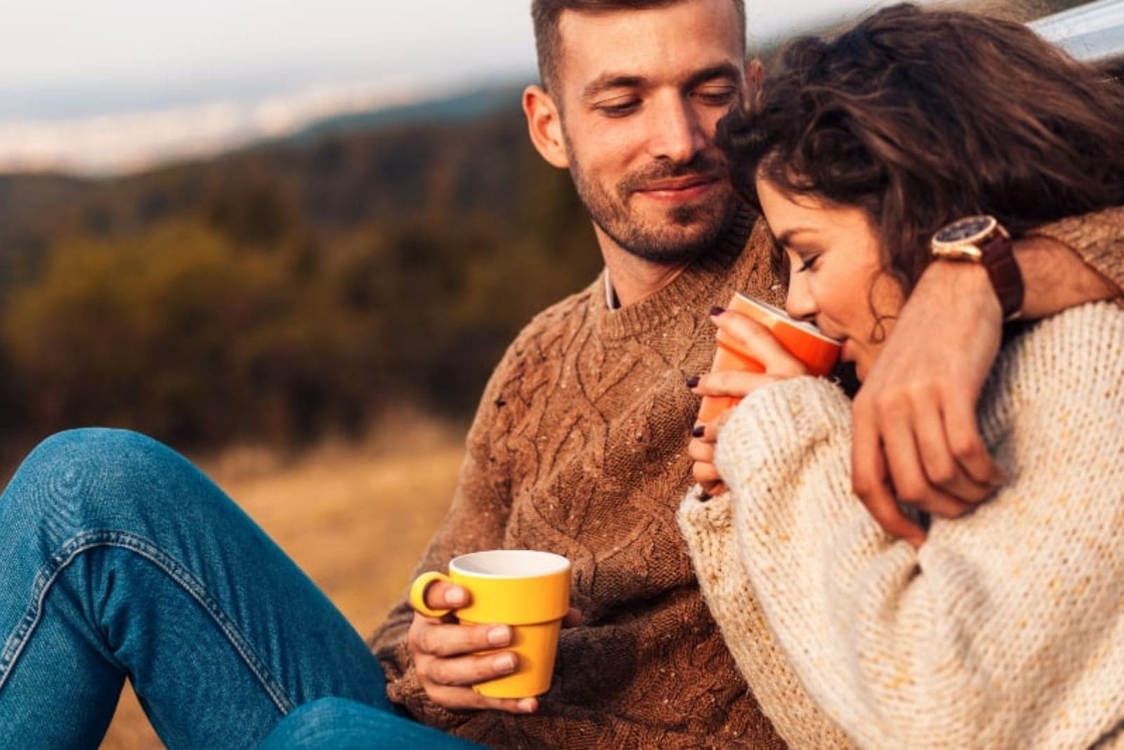 una pareja de enamorados abrazándose al aire libre y tomando café