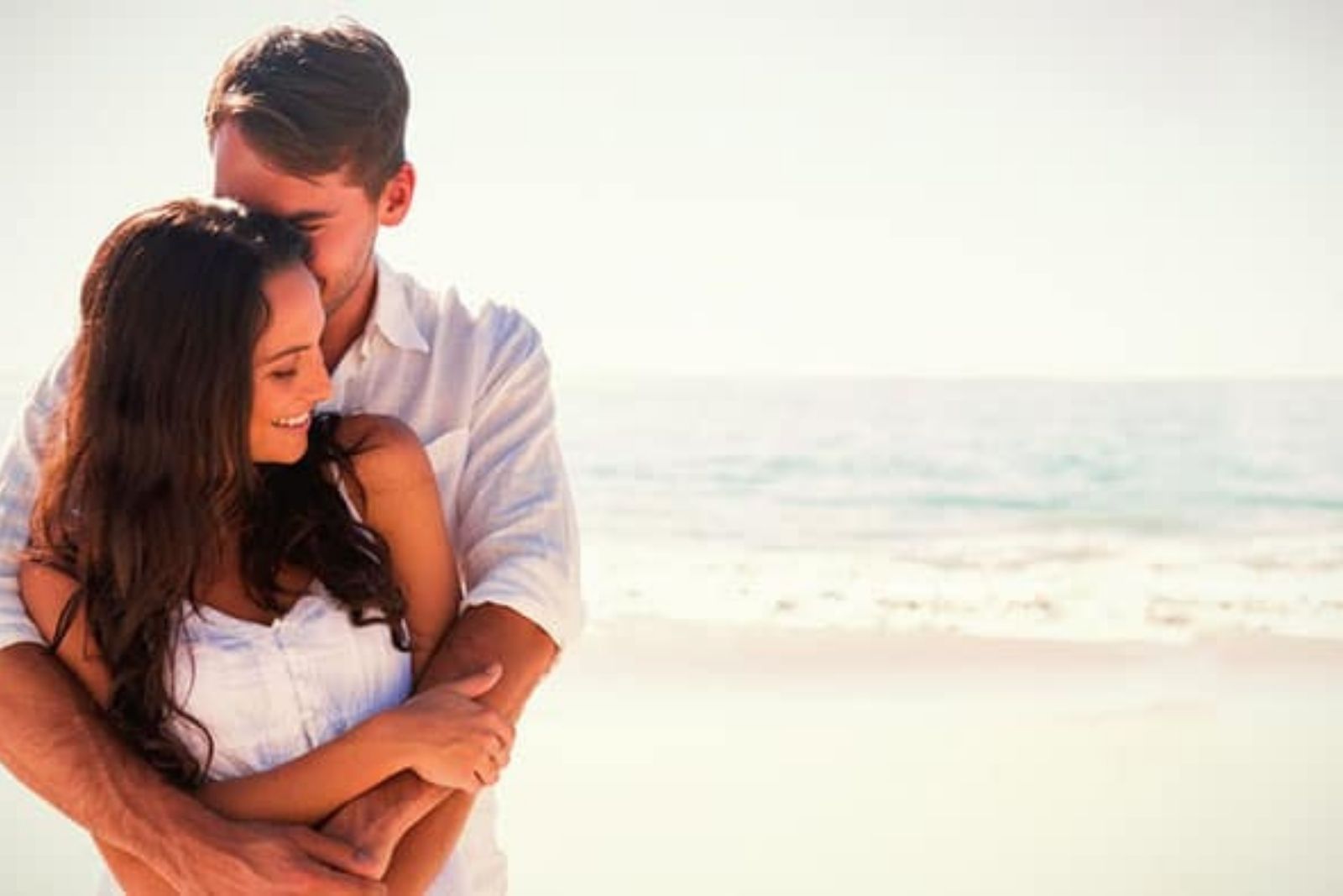 un hombre abraza a una mujer en la playa