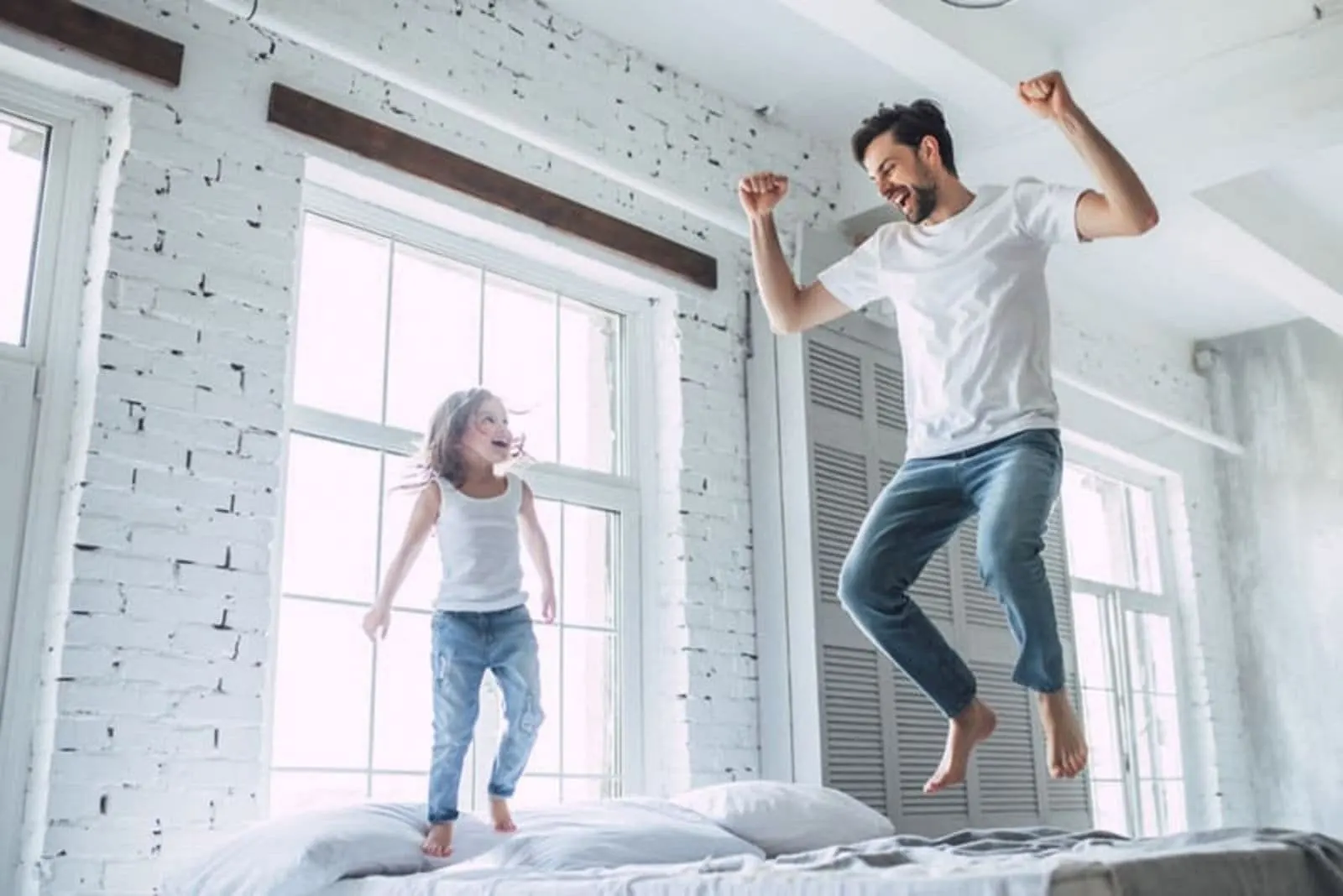 a man with a child jumps on the bed