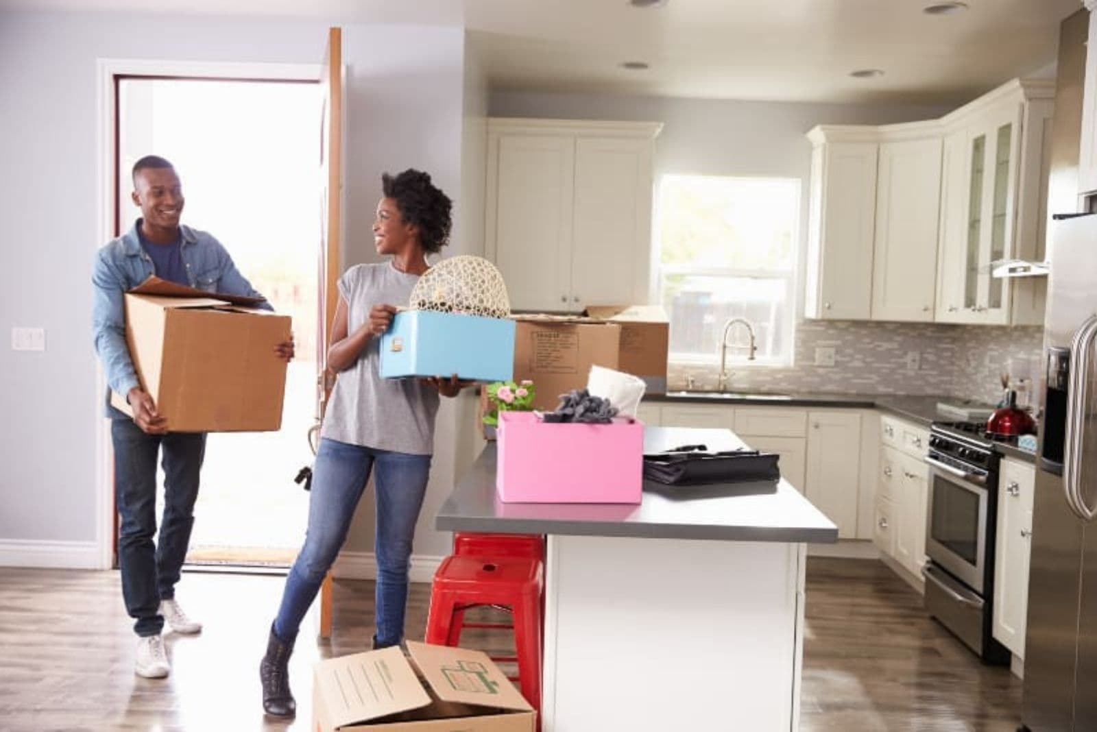 a smiling black man and woman bring things into the house