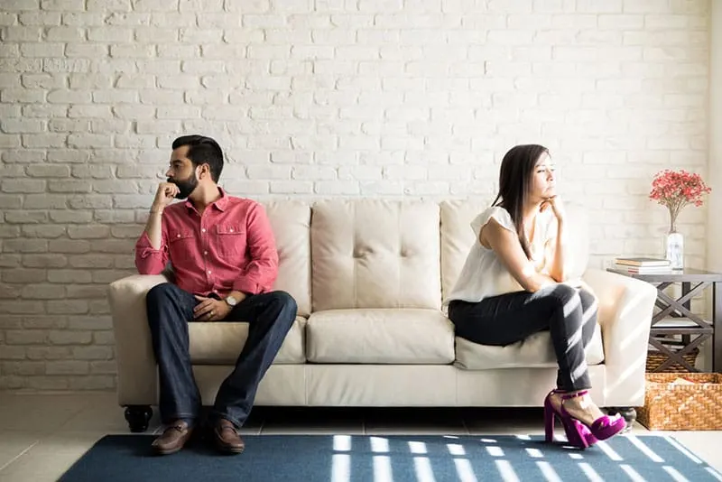 couple in argue sitting apart on the couch