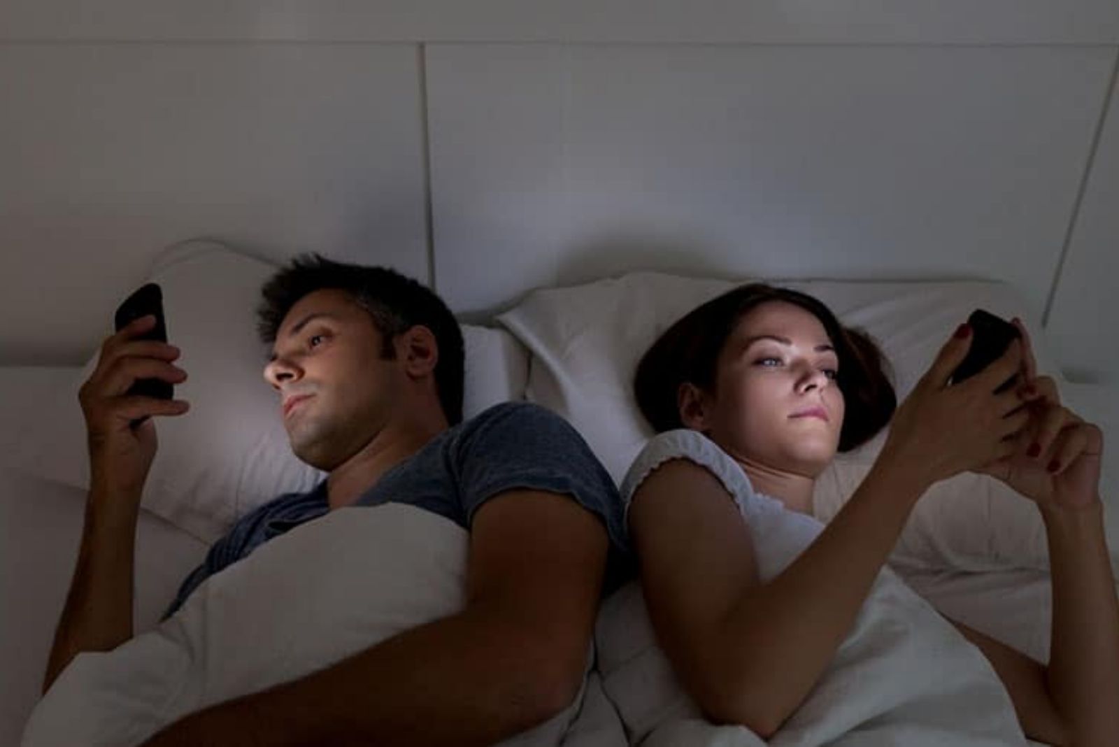 pareja que no habla y usa el móvil en la cama