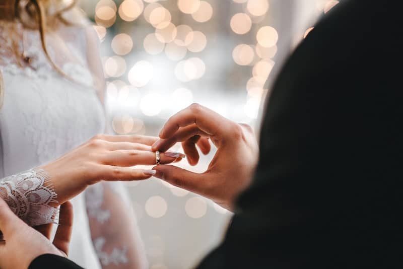 groom putting wedding finger on his bride
