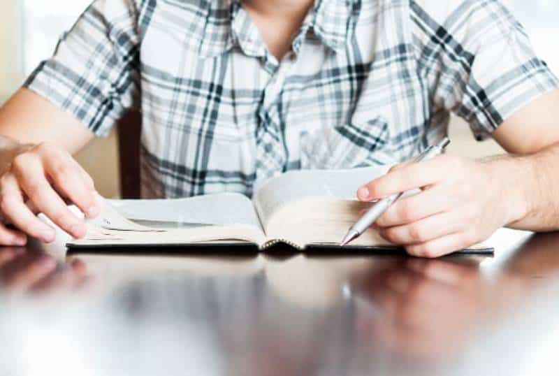 ragazzo che studia tenendo in mano una penna