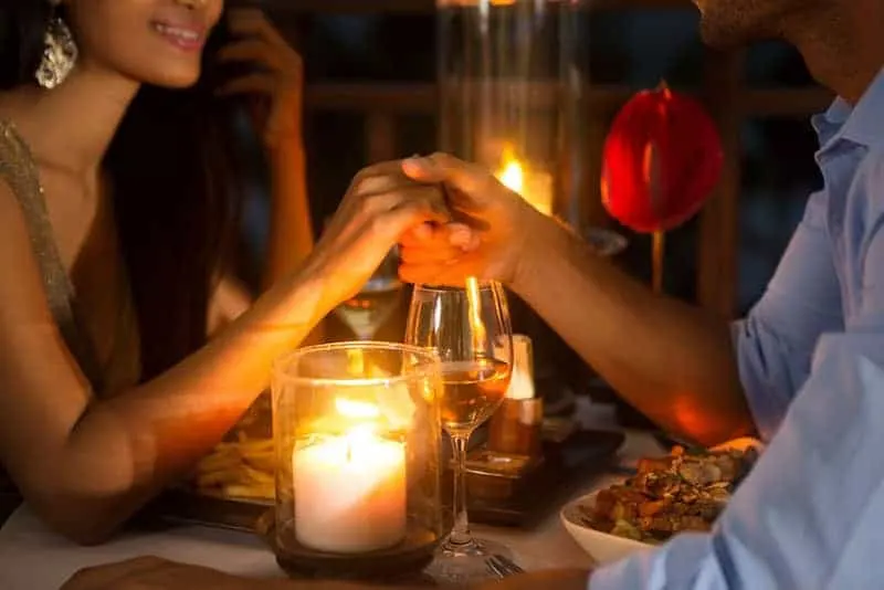 lovely couple hold hands while having a dinner date