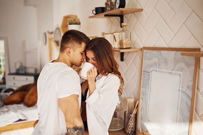 uomo che abbraccia donna che beve caffè