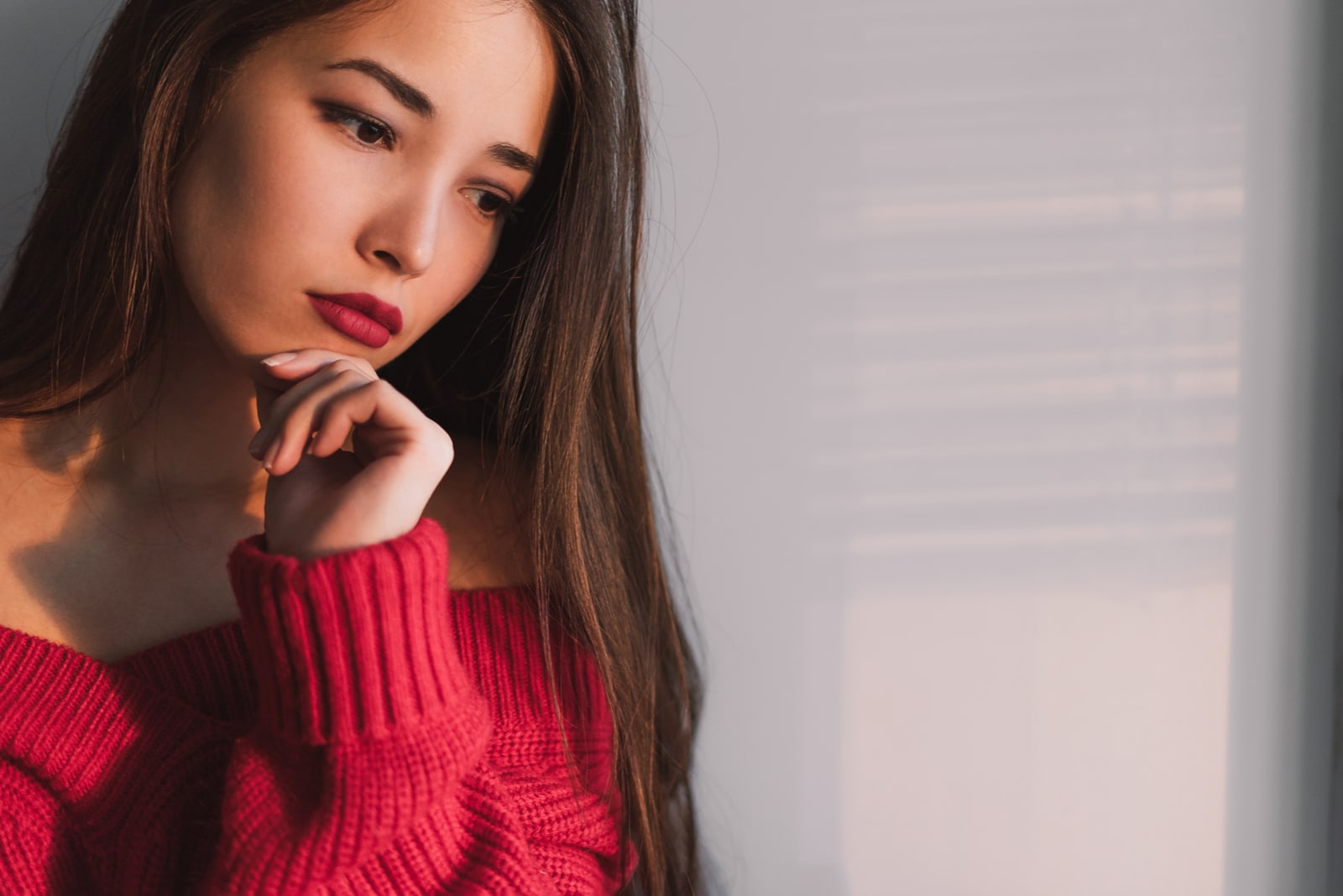 portrait of a sad beautiful asian woman in a pink sweater