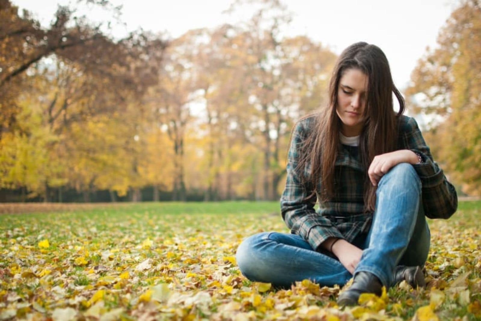 sad woman sitting in nature - autumn