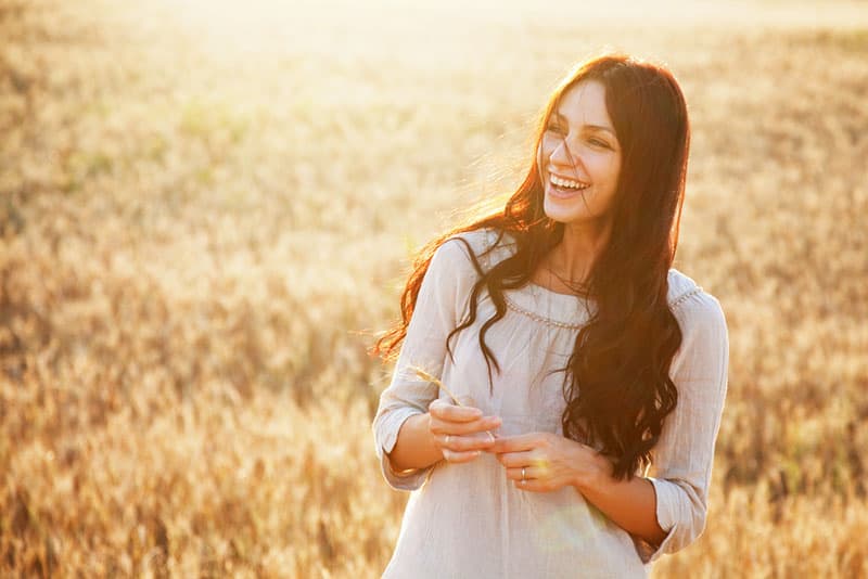 Beautiful brunette lady in wheat field at sunset