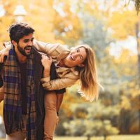 Pareja joven y sonriente disfrutando del otoño en el parque.