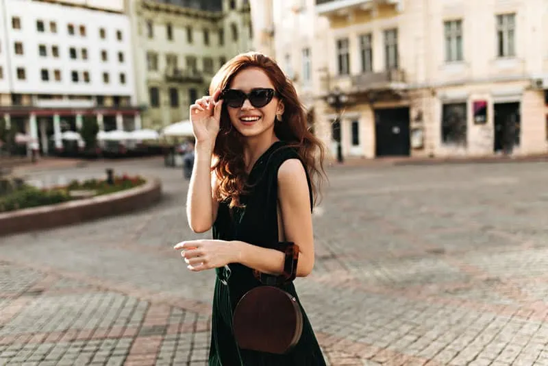 Stylish lady in sunglasses walking through city