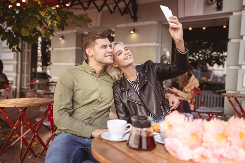 Hermosa joven tomando selfie con su novio guapo alegre