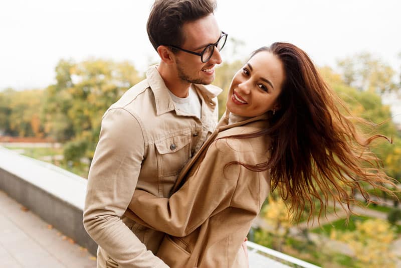 Happy romantic moments of lovely couple dancing and fooling around in park during dating.