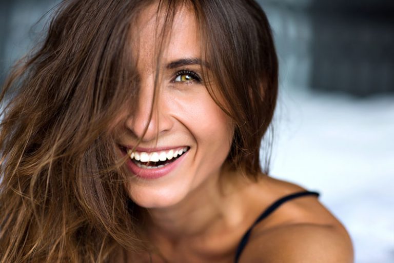 Ritratto mattutino ravvicinato di bella donna sorridente con occhi verdi, viso sensuale e fresco, emozioni positive.