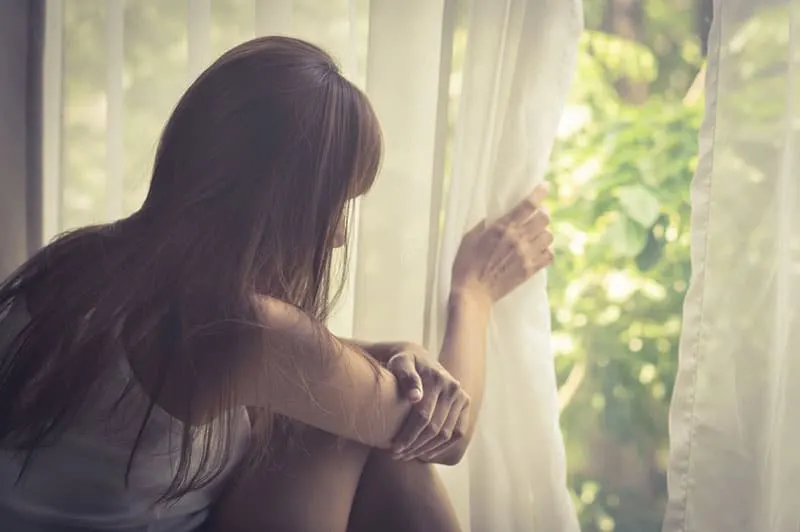 Sad girl looking out of window,vintage filtered.