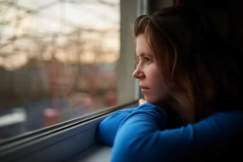 lonely girl thinking about something near window