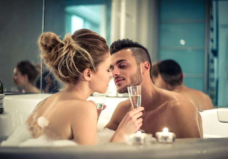 Giovane coppia felice che si gode il bagno nella vasca idromassaggio - Coppia di amanti che si baciano in una piscina idromassaggio