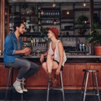 Fotografia de um jovem casal sentado ao balcão de um café