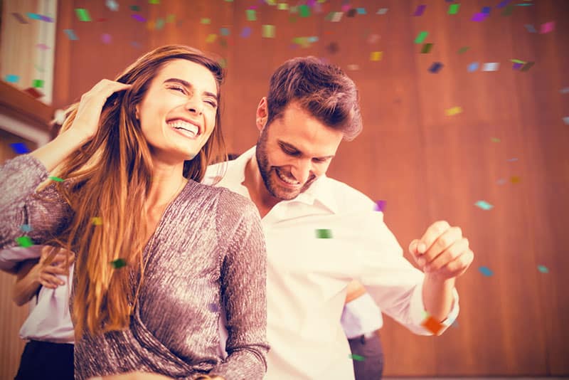 Cheerful young dancing couple against flying colours