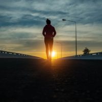 silueta de mujer caminando por la calle al atardecer.