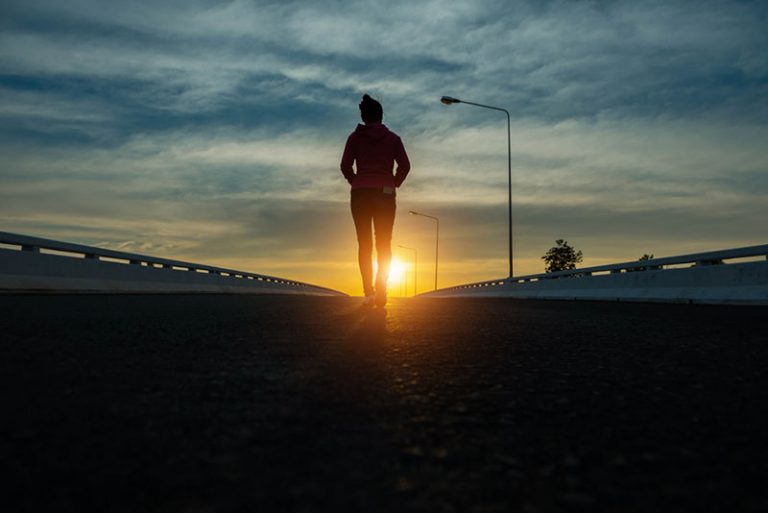 silhouette woman walking on the street at sunset.