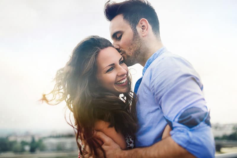 Hermosa pareja de enamorados saliendo al aire libre y sonriendo