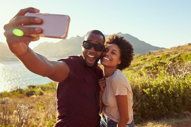 Una giovane coppia posa per un selfie in vacanza sulla cima di una scogliera