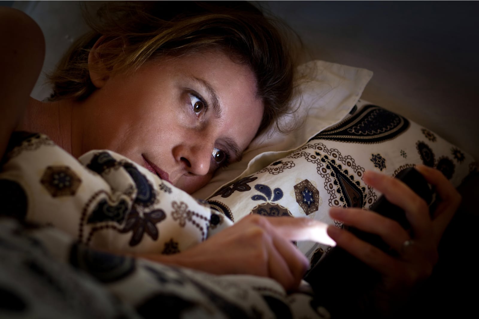 the blonde is lying in bed and using her cell phone