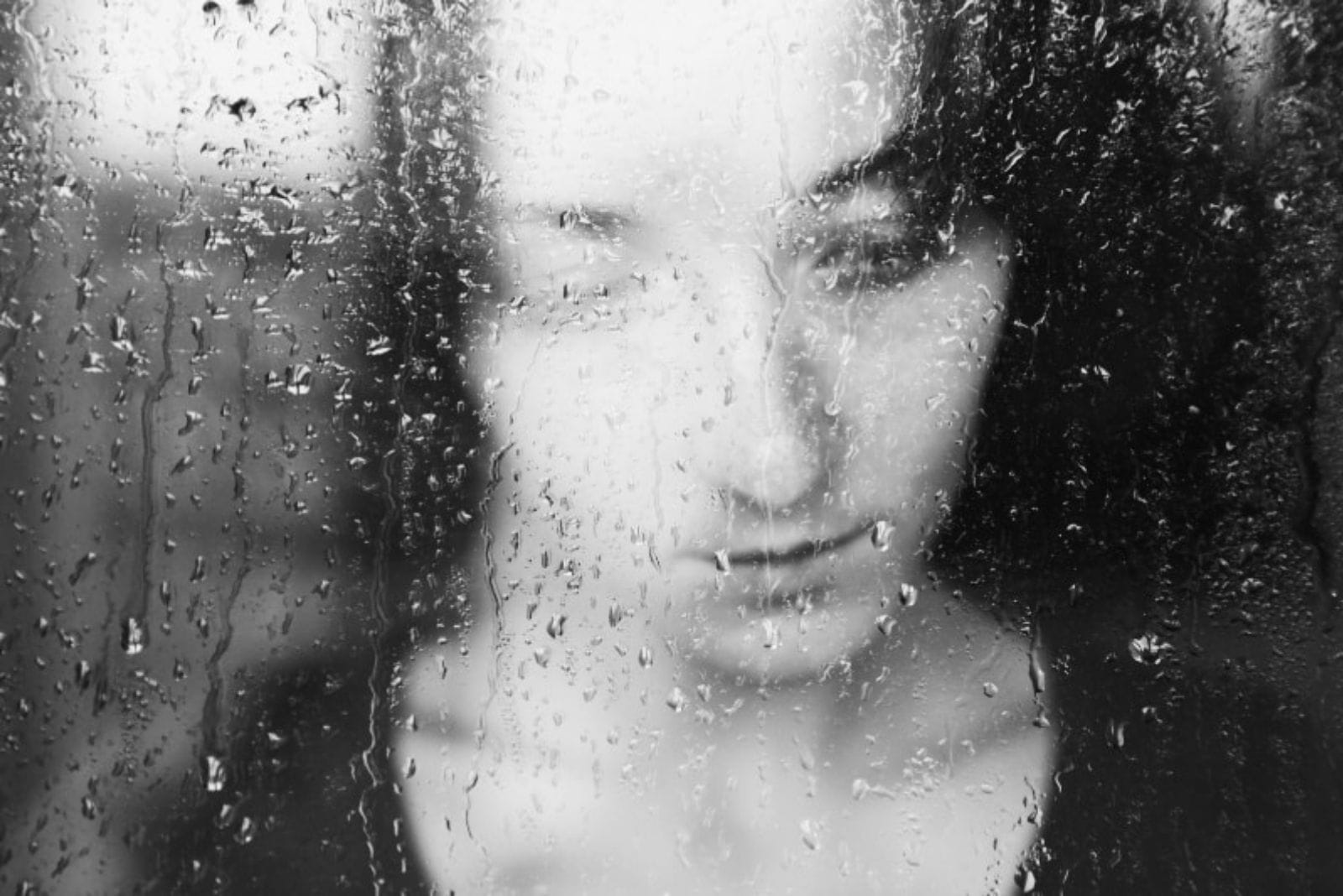woman sad behind window - raindrops