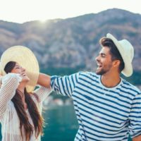 the man and woman laugh as he touches her hat