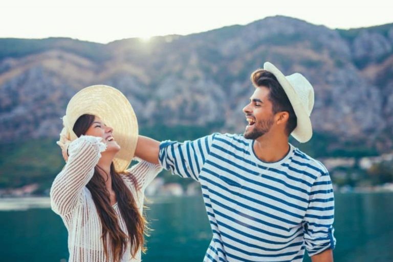 l'uomo e la donna ridono mentre lui tocca il cappello di lei