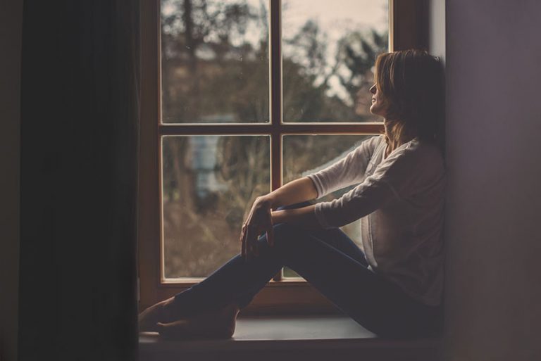 sad young woman sitting by the window