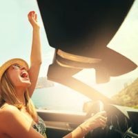 young woman driving car and laughing