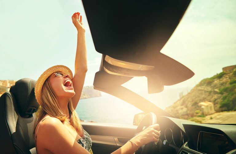 young woman driving car and laughing